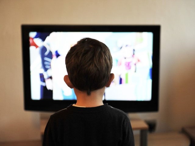 chłopiec ogląda telewizję tyłem do obiektywu aparatu