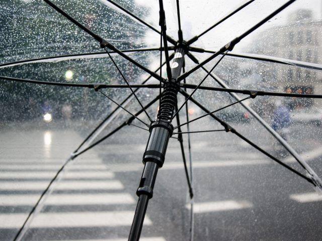 parasol przeźroczysty z kroplami deszczu przez niego widać przejście dla pieszych i ulicę