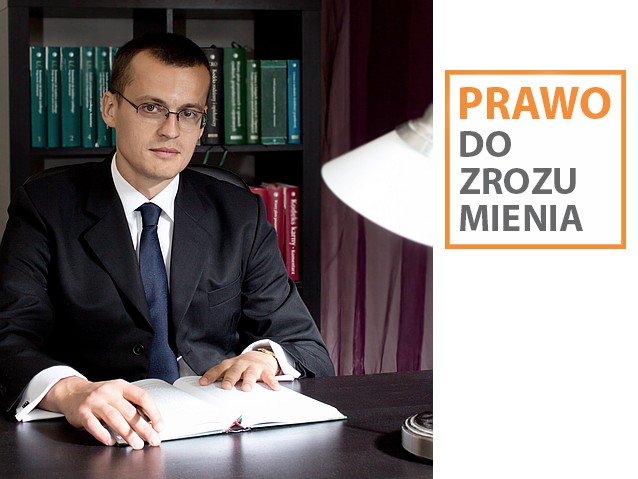 Adwokat Grzegorz Jaroszczyk siedzi przy biurku, za nim na regale stoją kodeksy i księgi prawnicze. Obok napis: Prawo do zrozumienia