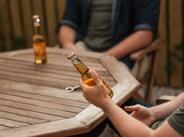Dwoje mężczyzn siedzi przy stoliku z butelkami piwa