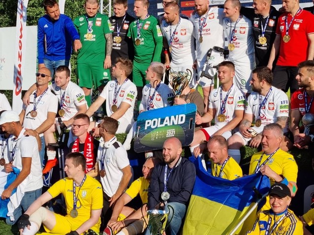 Reprezentanci Polski i Ukrainy pozują do zdjęcia w strojach piłkarskich. Polacy trzymają puchar