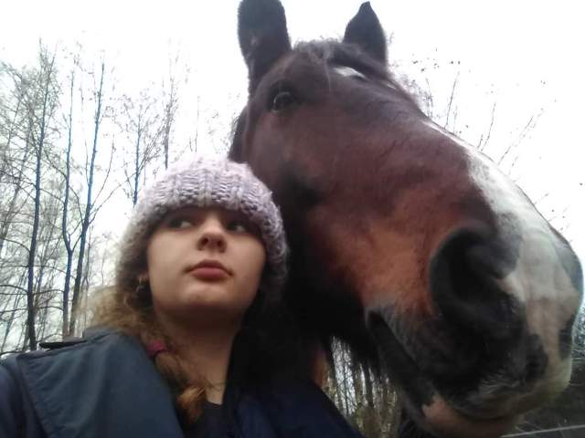 Julka w czapce przytulona do konia na dworze