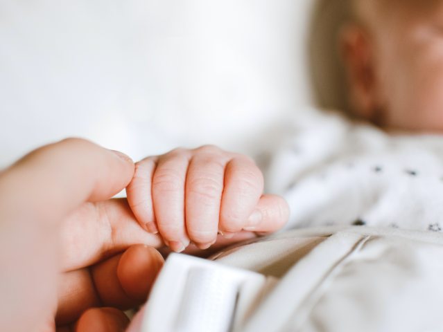 zarys niemowlęcia jego ręka trzyma palec dłoni dorosłego