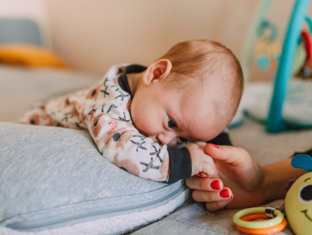 noworodek opiera głowę na poduszce kobieca ręka trzyma jego rękę