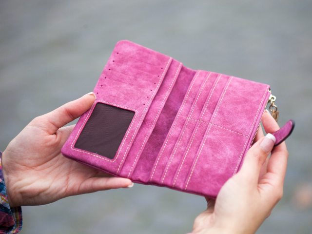 kobieta trzyma w dłoniach różowy portfel