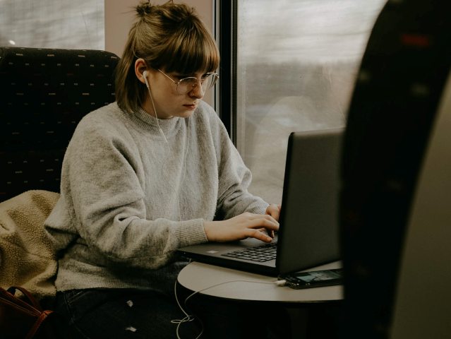dziewczyna w okularach siedzi i pracuje na laptopie