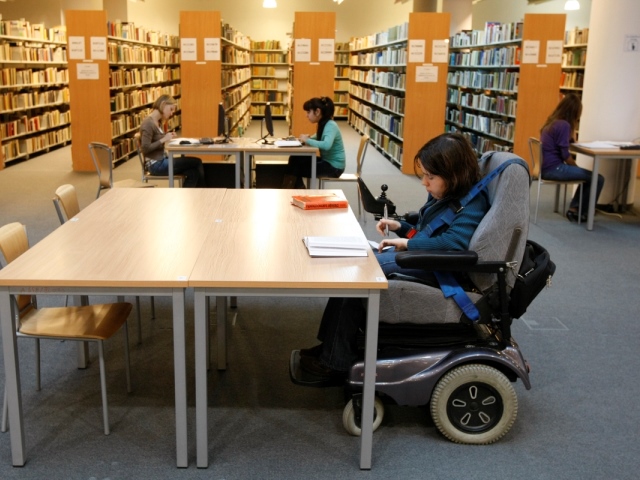 uczennice jedna  na wózku siedzą przy stolikach w bibliotece