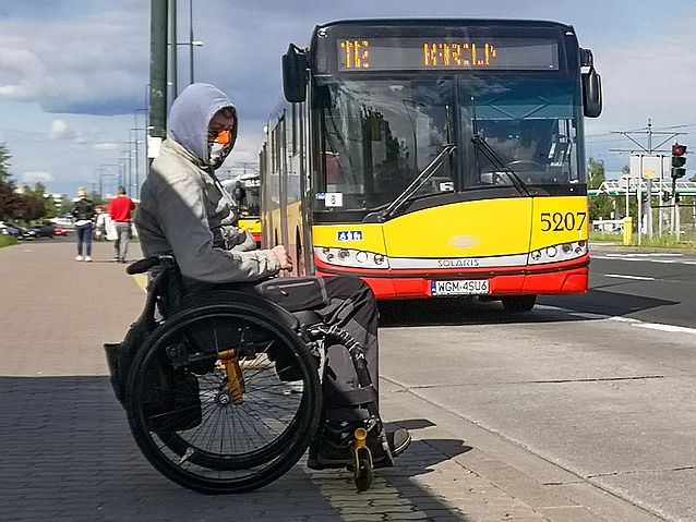 chłopak na wózku w maseczce na przystanku autobusowym, podjeżdża autobus