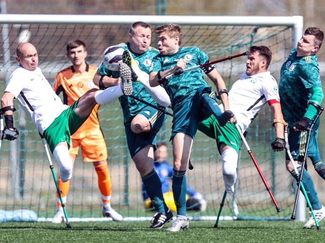 kilku zawodników dwóch drużyn ampfutbolu walczą o piłkę pod bramką