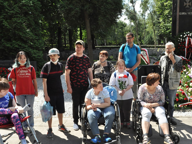 kilka osób z niepełnosprawnością pozują do zdjęcia, w tle park
