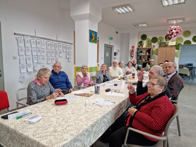 Osoby starsze przy stole uczące się języka migowego