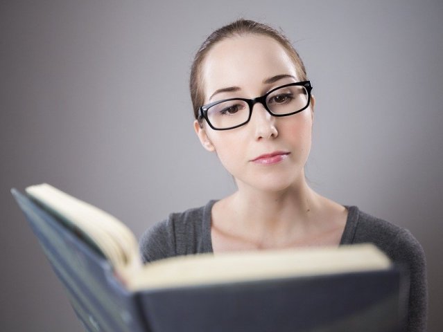 kobieta w czarnych okularach czyta książkę