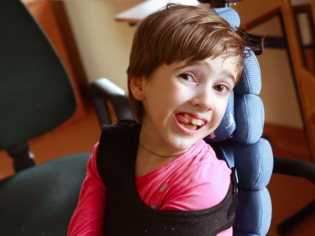Uśmiechnięta dziewczynka przypieta do wózka elektrycznego
