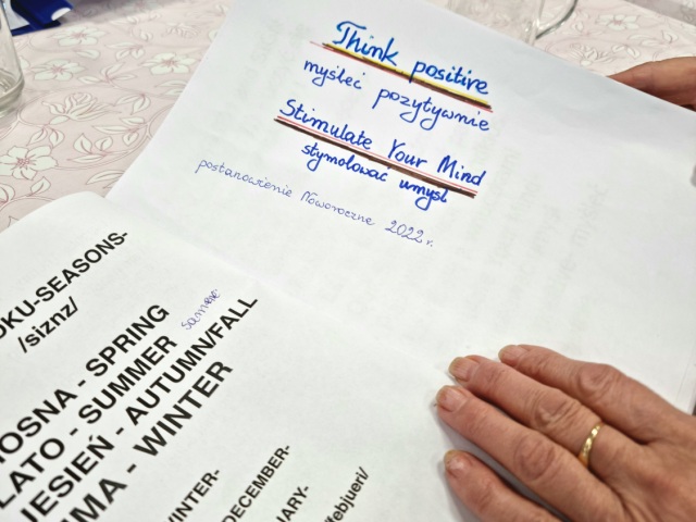 Dłoń osoby z Alzheimerem, która trzyma notatki do nauki języka angielskiego.