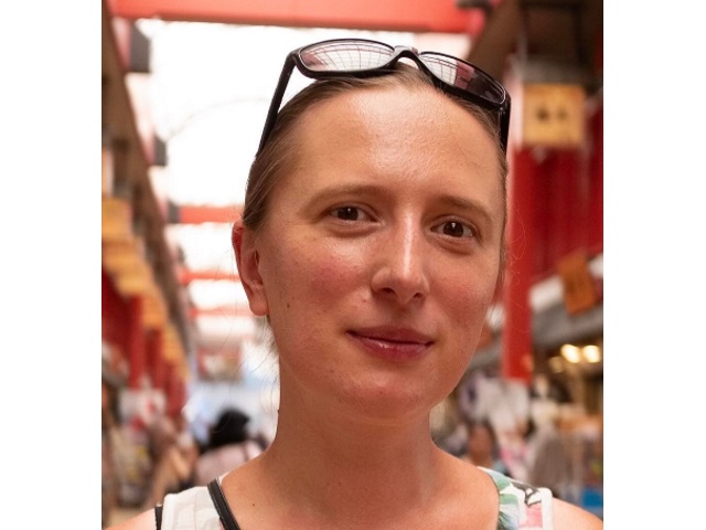 Ewa Dobiła. Zdjęcie portretowe kobiety stojącej w alejce orientalnego bazaru. 