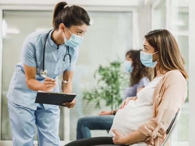 Ginekolożka i pacjentka w ciąży siedząca na korytarzu.