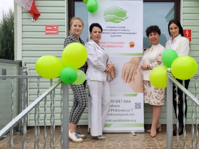 Irena Mysłek-Sikora wraz ze swoimi pracowniczkami stoi przy wejsciu do Domu dziennego 