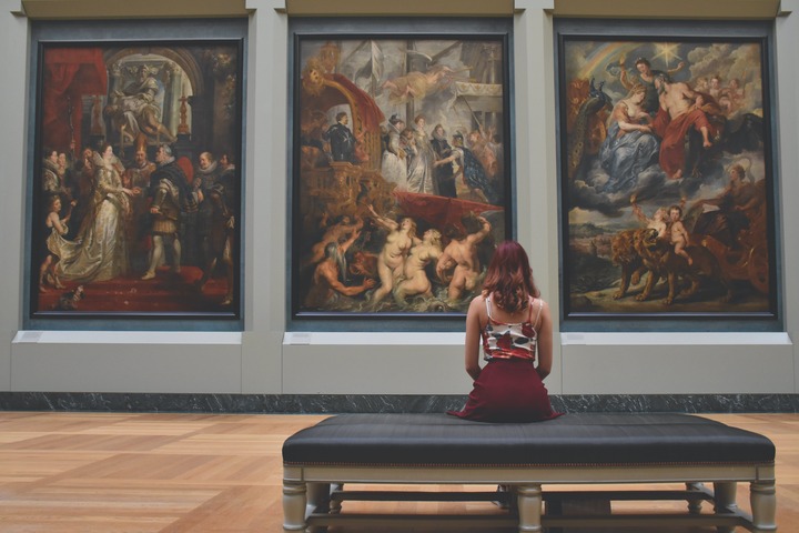 dziewczyna siedzi na ławce w muzeum, patrzy na obrazy