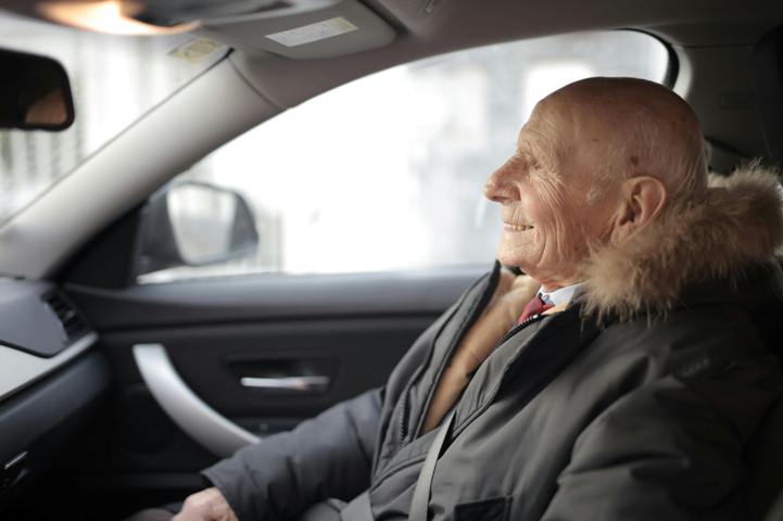starszy mężczyzna siedzący w samochodzie.