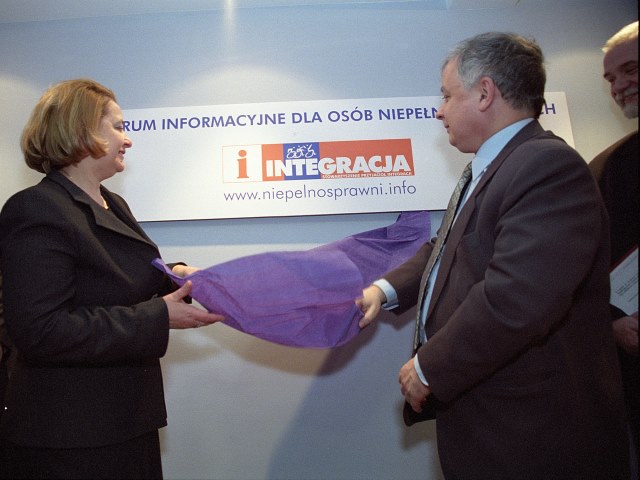 Lech Kaczyński i Jolanta Banach pełnomocnik rządu ds. osób niepełnosprawnych ściągają wstęgę z napisu centrum informacyjne dla osób niepełnosprawnych|