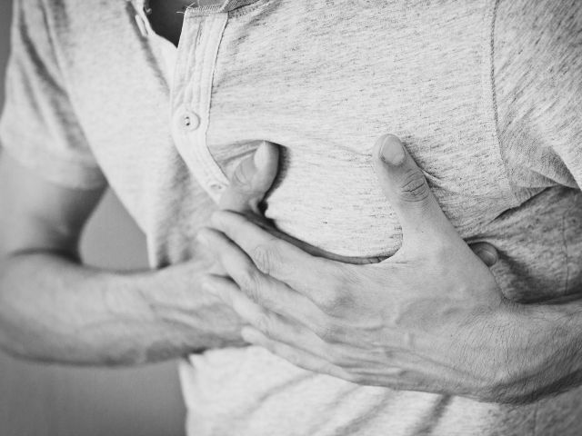 mężczyzna trzyma się rękami za klatkę piersiową w okolicy serca