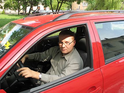 Łukasz Bednarski za kierownicą czerwonego samochodu