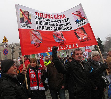 Manifestacja. Na transparencie przekreślone twarze władz PZG i hasło 