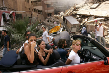 zdjęcie: grupa młodych Libańczyków przejeżdżających przez zbombardowaną dzielnicę Południowego Bejrutu