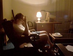 mężczyzna z papierosem w dłoni siedzi przy zapalonej lampce