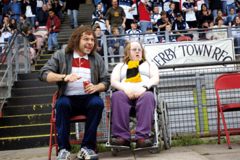 scena z filmu Mała Brytania: dwóch mężczyzn, jeden na wózku, na meczu piłkarskim