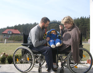rodzice na wózkach inwalidzkich razem trzymają nosidełko