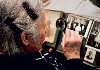 starsza kobieta oglądająca album z lupą w dłoni