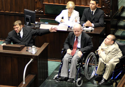 Trzech posłów na wózkach, na dostosowanej mównicy w Sejmie. Od lewej: przemawiający Sławomir Piechota, Jan Filip Libicki i Marek Plura