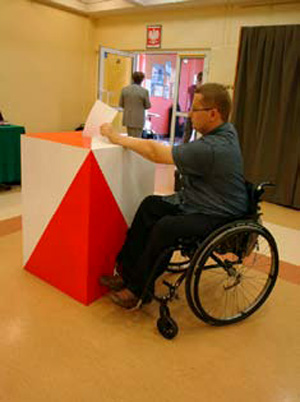 Na zdjęciu: Wyborca z niepełnosprawnością ruchową przy urnie wyborczej