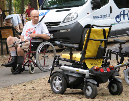 Na zdjęciu: mężczyzna z niepełnosprawnością ogląda ofertę wózków elektrycznych