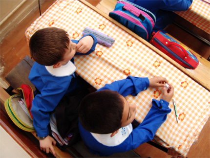 Dwójka dzieci siedzi w ławce szkolnej