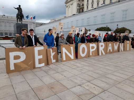 Pod Pałacem Prezydenckim stoi grupa protestujących. W rękach trymają kartony, na których są litery tworzące napis pełnosprawni